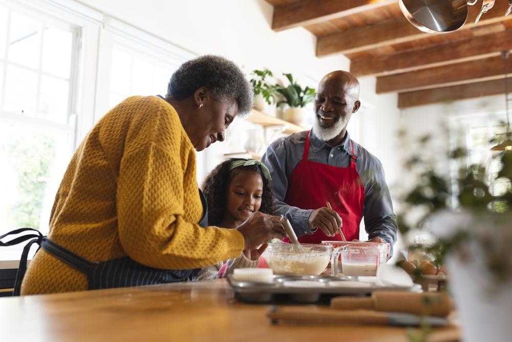 Happy african american couple cooking in the kitchen with their young granddaughter. 